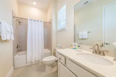 a white bathroom with a sink and a toilet at Blue Sky Cottage Near Disney With Private Hot Tub & Margaritaville Resort & Island H20 Waterpark Access - 3008Sr in Orlando