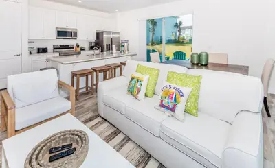 a living room with a white couch and a kitchen at Comfy And Delightful Villa Near Disney With Margaritaville Resort & Island H20 Access - 8185Su in Orlando