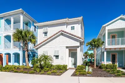 a white house with palm trees in front of it at Cozy Cottage With Private Pool Near Disney With Margaritaville Resort & Island H2O Access - 8028Kd in Orlando