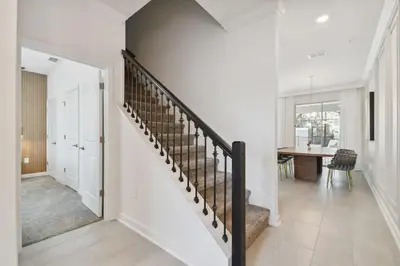 a white hallway with a staircase in a house at Storey Lake - Piscina privativa Cama King 4BD/3BA in Kissimmee