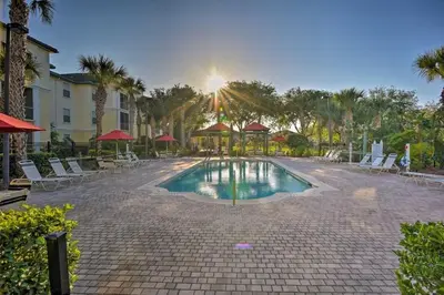 a pool in a courtyard with chairs and umbrellas at Conforto e Espaço: Apt de 2Q e 2B em Legacy Dunes in Kissimmee