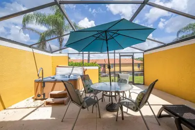a patio with a table and a blue umbrella at Cozy 2Bd Spa & Jacuzzi Close to Disney at Encantada 3029 in Kissimmee
