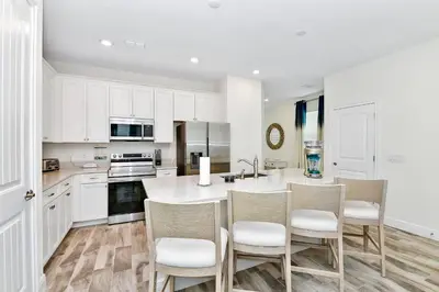 a kitchen with white cabinets and a kitchen island with chairs at Bright Blue Villa Near Disney With Margaritaville Resort & Island H20 Waterpark Access - 3085Cs in Orlando