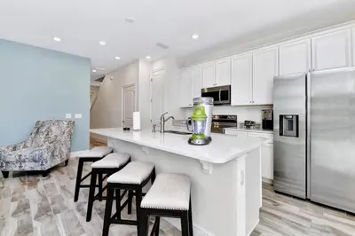 a kitchen with white cabinets and a kitchen island with stools at Pleasant Villa Near Disney With Margaritaville Resort & Island H20 Access - 2916Or in Orlando