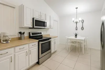 a kitchen with white cabinets and a stove top oven at Vista para o lago Casa c/piscina in Kissimmee