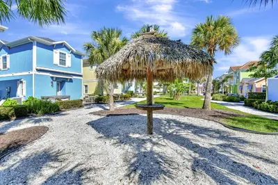 a straw umbrella in front of a blue house at Casa Blanca Cottage With Hot Tub Near Disney With Margaritaville Resort & Island H2O Access - 8032Su in Orlando