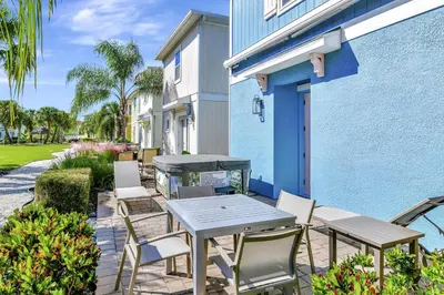 a patio with a table and chairs next to a building at Casa Blanca Cottage With Hot Tub Near Disney With Margaritaville Resort & Island H2O Access - 8032Su in Orlando