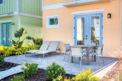 a patio with a table and chairs in front of a building at Sunset Cottage Near Disney With Margaritaville Resort & Island H2O Access - 8065Ls in Orlando