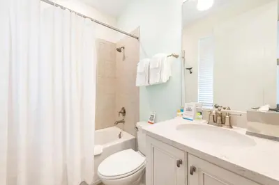 a white bathroom with a toilet and a sink at No Shoes Retreat! Cottage With Hot Tub Near Disney With Margaritaville Resort & Island H2O Access - 8085Dr in Orlando