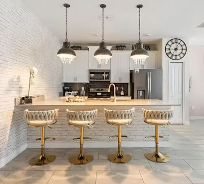 a kitchen with white cabinets and gold bar stools at 5 BR Disney themed bedrooms SL 4825 in Kissimmee