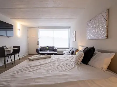 a bedroom with a large white bed and a living room at Fun filled 1BR Close to Disney Parks With Lake view in Vineland