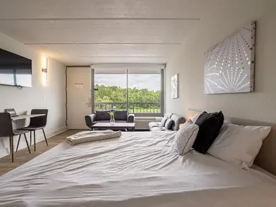 a bedroom with a large white bed and a living room at Fun filled 1BR Close to Disney Parks With Lake view in Vineland