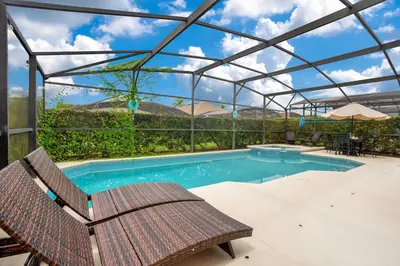 a swimming pool with a chair and an umbrella at Relaxing Retreat in the Windsor Palms Resort in Kissimmee