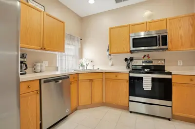 a kitchen with wooden cabinets and a stove and microwave at Relaxing Retreat in the Windsor Palms Resort in Kissimmee