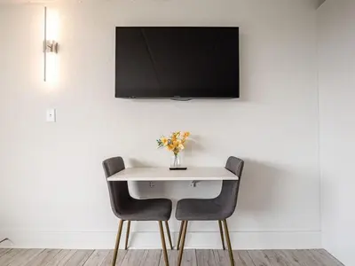 a white table with two chairs and a tv on a wall at Lovely 1BR Suite Minutes to Disney With Lake view in Vineland
