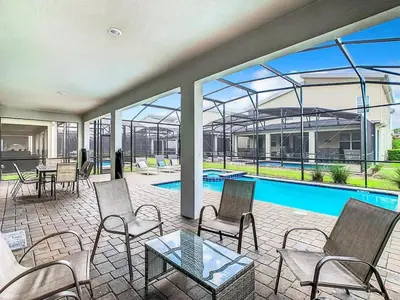 a patio with chairs and a table and a swimming pool at Once Upon a Villa in Kissimmee