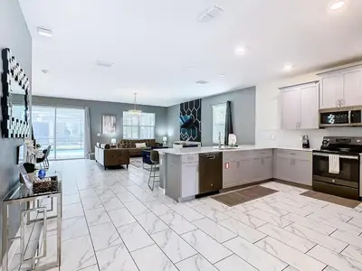 a large kitchen with white appliances and a living room at Once Upon a Villa in Kissimmee