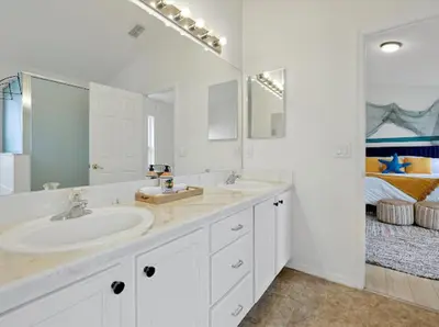 a bathroom with two sinks and a large mirror at 6BD - Pool, BBQ & Movie Theater - 10 Mins to Disney in Kissimmee