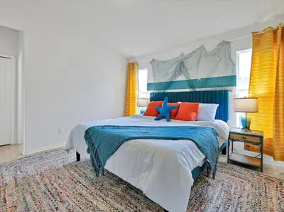 a bedroom with a large bed with orange and blue pillows at 6BD - Pool, BBQ & Movie Theater - 10 Mins to Disney in Kissimmee