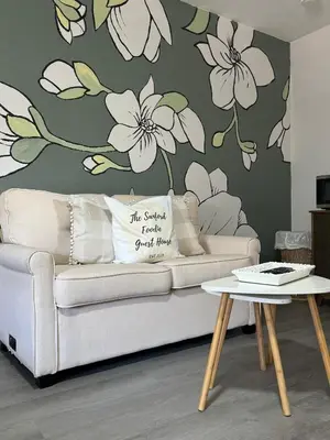 a living room with a couch with a flower wall mural at The Sanford Foodie Guest House in Sanford