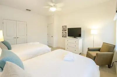 a hotel room with two beds and a chair and a television at 2612 LunaPi Villa 7Bd Private Pool and Family Room in Kissimmee