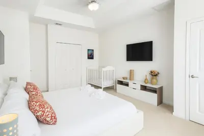 a white living room with a white couch and a tv at 2612 LunaPi Villa 7Bd Private Pool and Family Room in Kissimmee