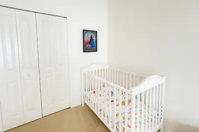 a white nursery with a crib and white cabinets at 2612 LunaPi Villa 7Bd Private Pool and Family Room in Kissimmee