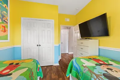 a yellow room with two beds and a flat screen tv at Condo in Gated Windsor Hills in Orlando