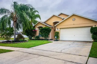 a house with a palm tree and a garage at 4 Bed Villa - Eagle Pointe - Kissimmee in Kissimmee