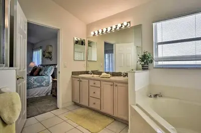 a bathroom with a tub and a sink and a mirror at 4 Bedroom Villa - Indian Creek in Kissimmee