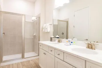 a white bathroom with a shower and two sinks at Paradise Cottage Near Disney With Margaritaville Resort & Island H2O Access - 8052Dr in Orlando