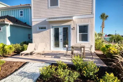 a patio with two chairs and a table in front of a house at Pleasant Cottage Near Disney With Margaritaville Resort & Island H20 Waterpark Access - 2972Sr in Orlando