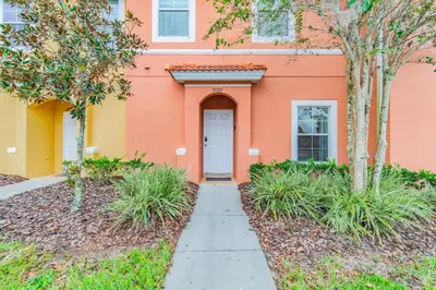 a orange building with a white door and trees at Casa 3Q Resort + Jacuzzi Perto Disney in Kissimmee