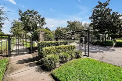 a black iron gate with bushes and grass at Entire home w/ Private Pool,Gated Near Disney in Orlando