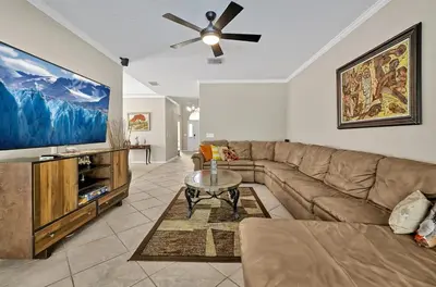 a living room with a couch and a ceiling fan at Entire home w/ Private Pool,Gated Near Disney in Orlando