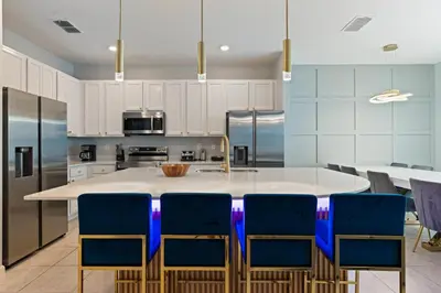 a kitchen with a large white island with blue chairs at New Home 8 Bedrooms At Bella Vida in Kissimmee