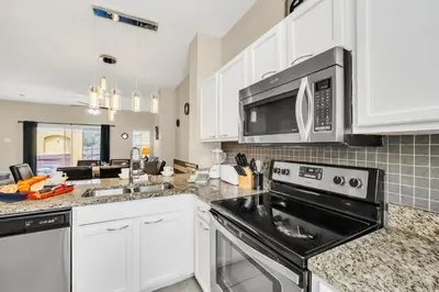 a kitchen with white cabinets and a black appliance at Family Oasis Cozy Retreat with Bunk Room in Kissimmee
