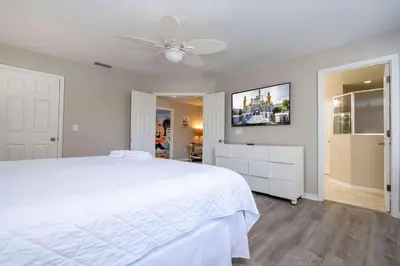 a bedroom with a white bed and a flat screen tv at 4BR Lakefront - Themed Rooms - Pool & BBQ! in Kissimmee