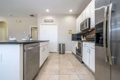 a kitchen with white cabinets and stainless steel appliances at 4BR Lakefront - Themed Rooms - Pool & BBQ! in Kissimmee
