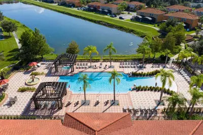 an overhead view of a swimming pool with palm trees and water at 4BR Lakefront - Themed Rooms - Pool & BBQ! in Kissimmee