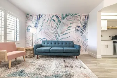 a blue couch in a living room with a tropical wallpaper at One bedroom unit near Epic Universe and Universal, free parking in Orlando