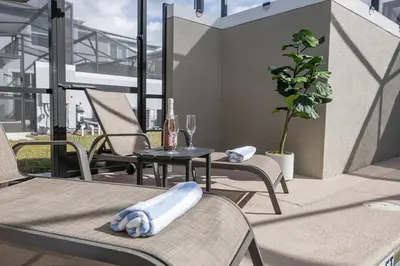 a patio with chairs and a table and a bottle of wine at EPIC STYLISh retreat With Free water park near Disney in Kissimmee