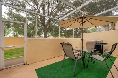 a patio with a table and chairs and an umbrella at Epic Arty Retreat near Disney in Kissimmee