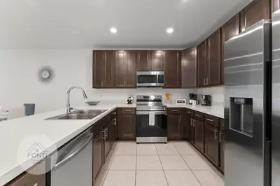 a kitchen with wooden cabinets and a stainless steel refrigerator at 4875 Resort Townhouse by Disney World Orlando in Kissimmee