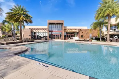 a large swimming pool with palm trees and a building at Luxury 4BR Townhouse Next to Disney Orlando 3173 in Orlando