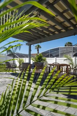 a patio with tables and chairs under a pergola at Vacation Oasis Home with Private Pool and Grill 8615 in Kissimmee