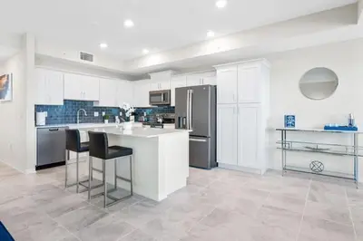 a kitchen with white cabinets and a counter with stools at Modern Storey Lake Resort Disney Orlando 3171-206 in Kissimmee