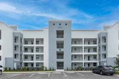 an apartment building with a car parked in a parking lot at Modern Storey Lake Resort Disney Orlando 3191-103 in Kissimmee