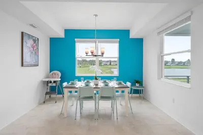 a dining room with a blue wall and a table and chairs at Modern Storey Lake Resort Disney Orlando 3191-106 in Kissimmee