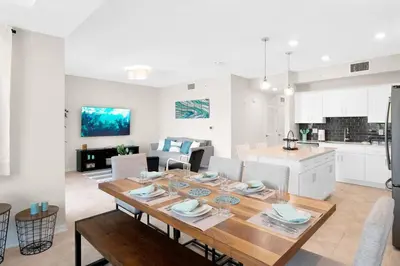 a kitchen and living room with a wooden table in a room at Modern Boho Storey Lake Resort Disney 3150-106 in Kissimmee